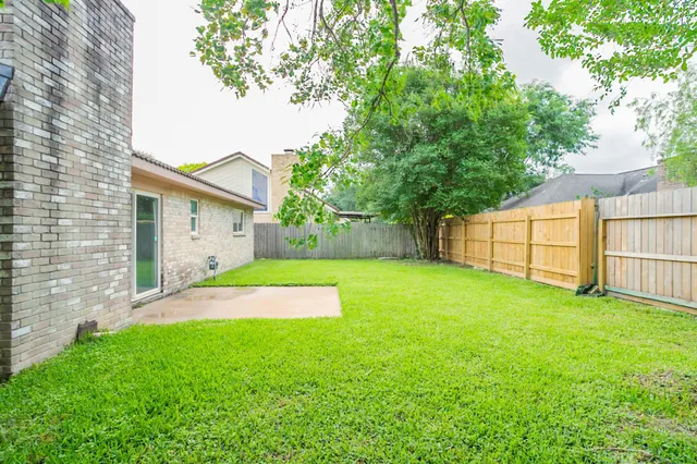 a view of backyard of house with wooden fence
