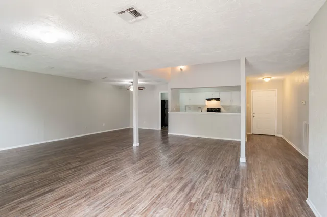 a view of a big room with wooden floor and a kitchen