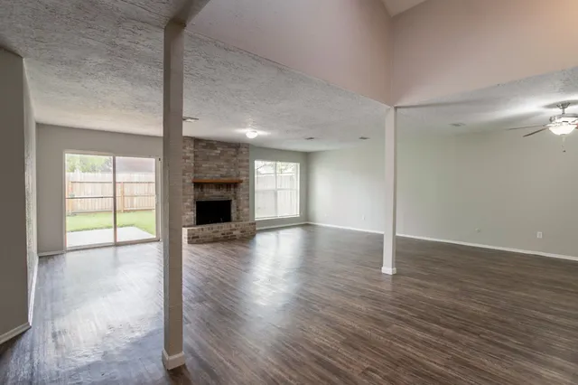 an empty room with wooden floor fireplace and windows