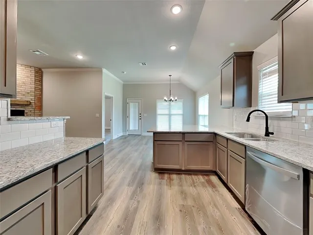 a large kitchen with stainless steel appliances a large counter top a stove a sink and a refrigerator