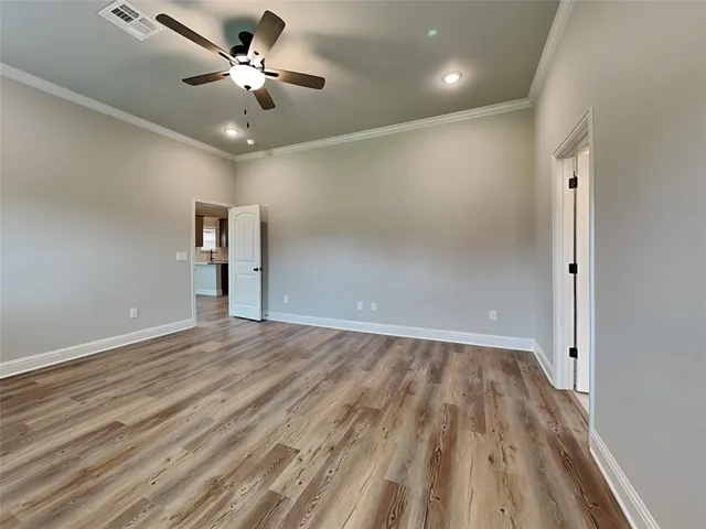 an empty room with wooden floor and a ceiling fan