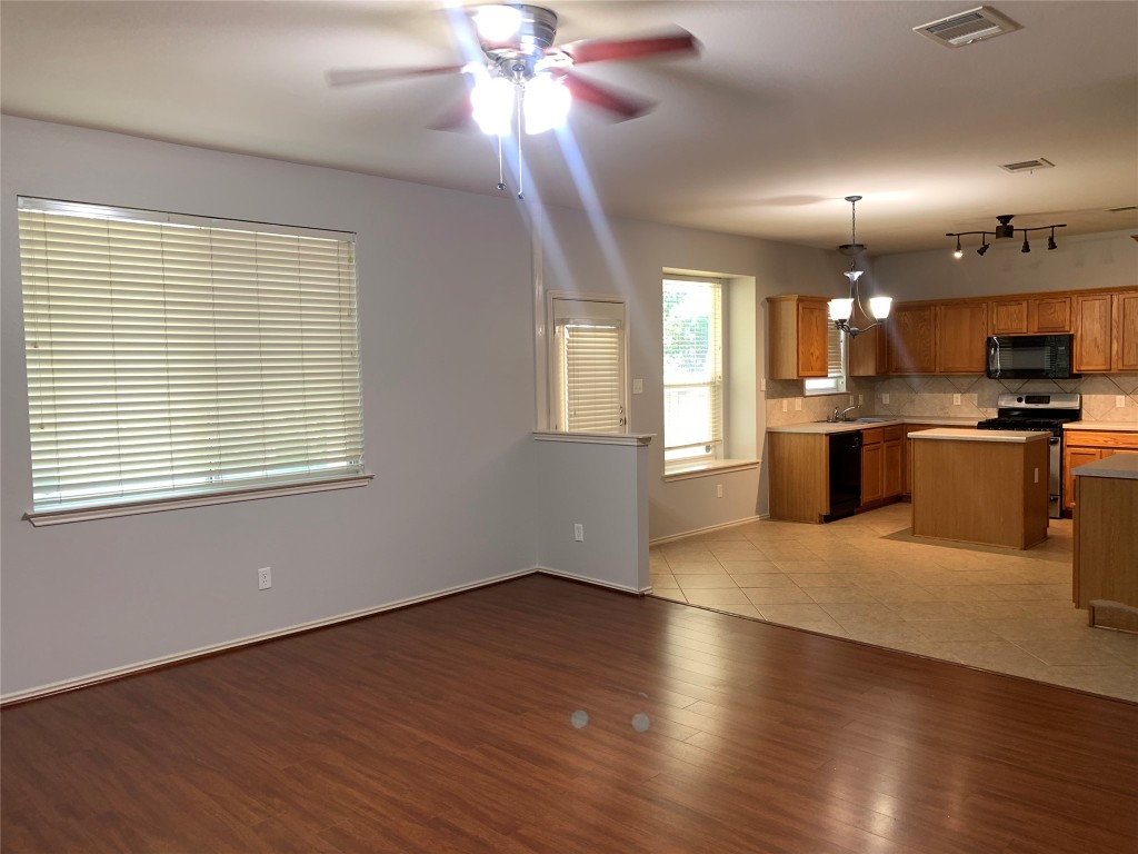 3667 Spring Canyon Trail Round Rock, TX 78681 - Photo 5 of 24 a view of a kitchen with a stove wooden cabinets and a chandelier