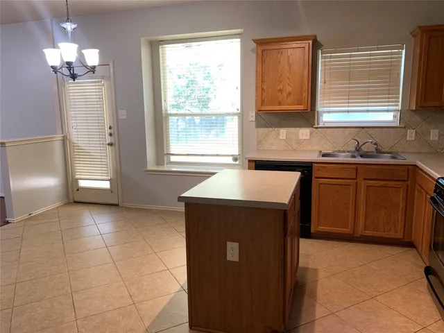 a kitchen with a sink a counter top space cabinets and window