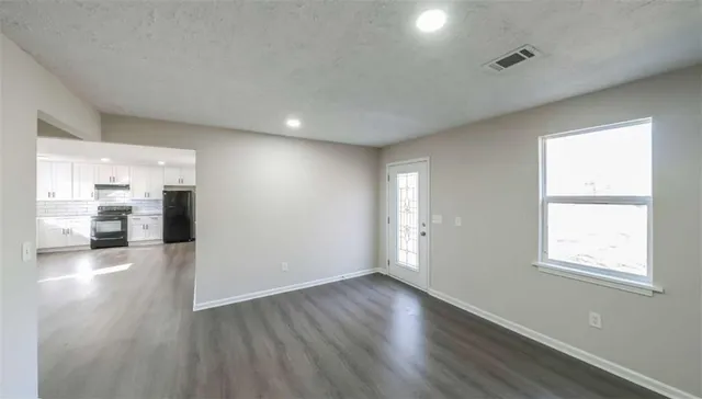 an empty room with wooden floor and windows