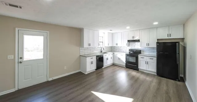 a kitchen with a white cabinets a sink and wooden floor