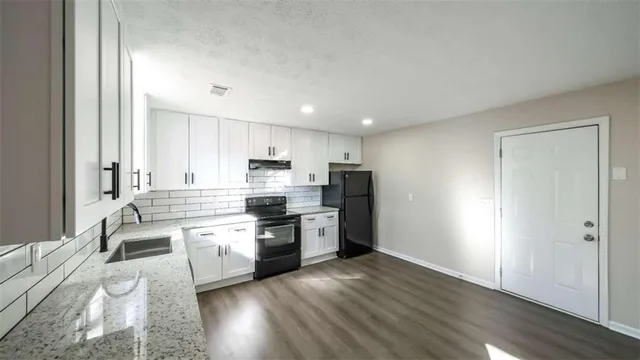 a kitchen with stainless steel appliances a sink a stove a refrigerator cabinets and a window