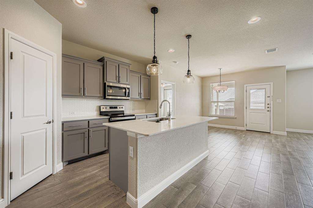 1829 Ruffian Road Granbury, TX 76049 - Photo 10 of 39 a kitchen with stainless steel appliances granite countertop a sink a stove a refrigerator and white cabinets with wooden floor