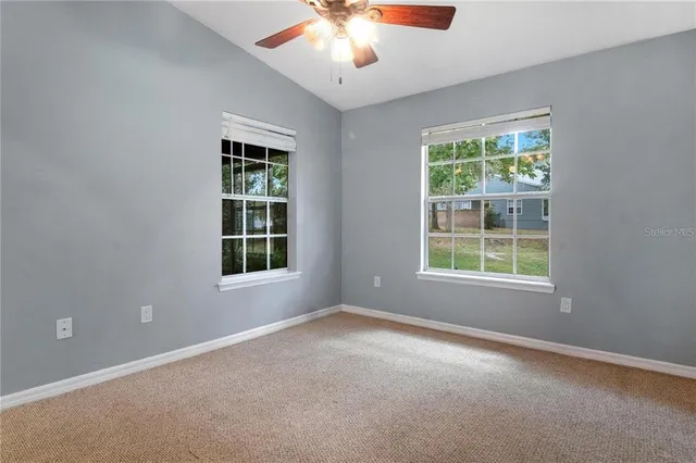 an empty room with a window and a ceiling fan