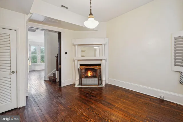 a view of an empty room with wooden floor fireplace and a window