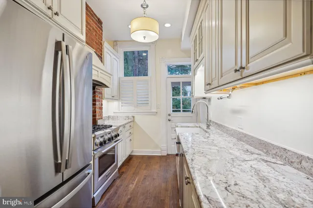 a kitchen with stainless steel appliances granite countertop a stove and a refrigerator with white cabinets