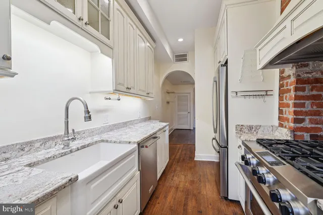 a kitchen with granite countertop a sink stove and cabinets