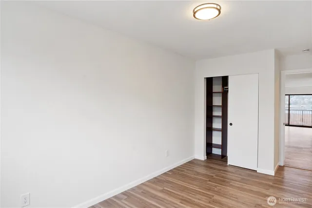 a view of an empty room with wooden floor and closet