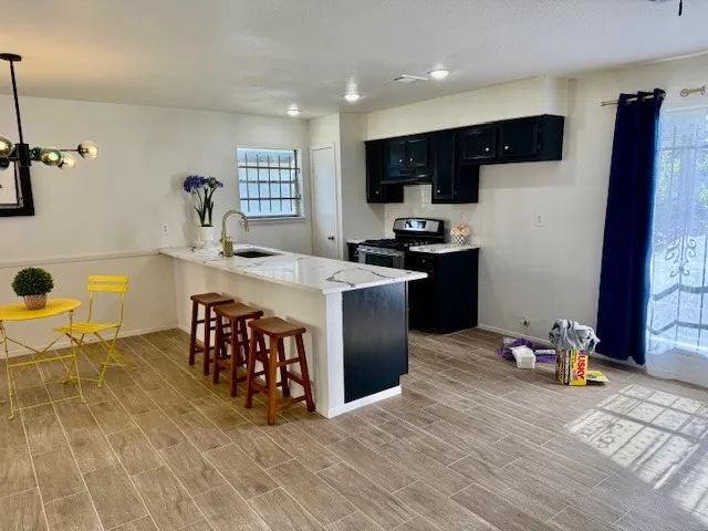 a kitchen with stainless steel appliances granite countertop a stove top oven a sink a dining table and chairs with wooden floor