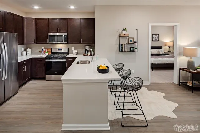 a kitchen with a refrigerator a stove top oven a sink dishwasher and white cabinets next to a window