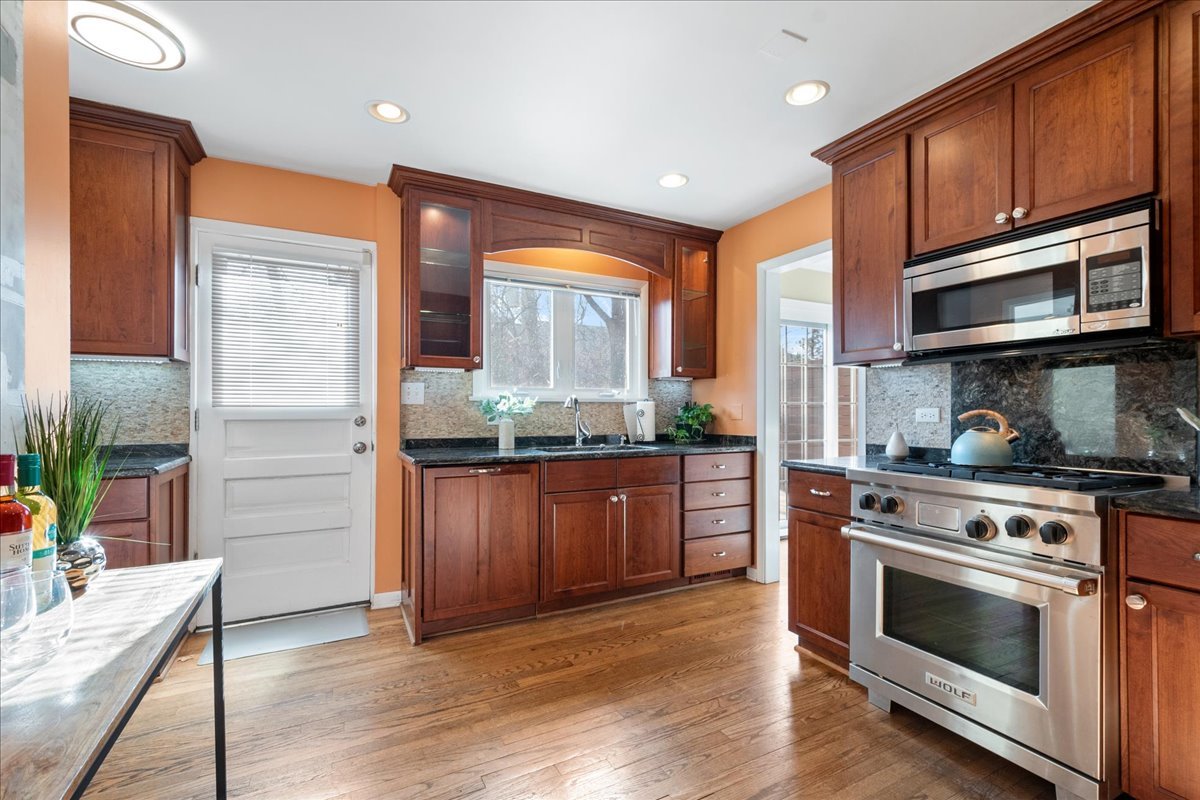 2440 Simpson Street Evanston, IL 60201 - Photo 11 of 34 a kitchen with kitchen island granite countertop wooden floors and stainless steel appliances