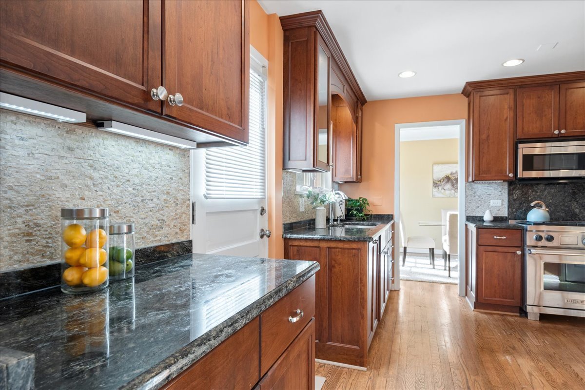 2440 Simpson Street Evanston, IL 60201 - Photo 14 of 34 a kitchen with stainless steel appliances granite countertop a sink a stove and a wooden floors