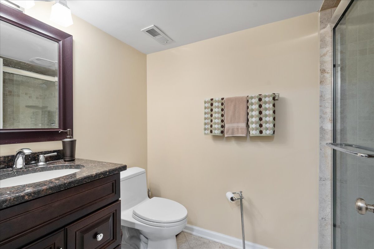 2440 Simpson Street Evanston, IL 60201 - Photo 19 of 34 a bathroom with a granite countertop toilet sink and mirror