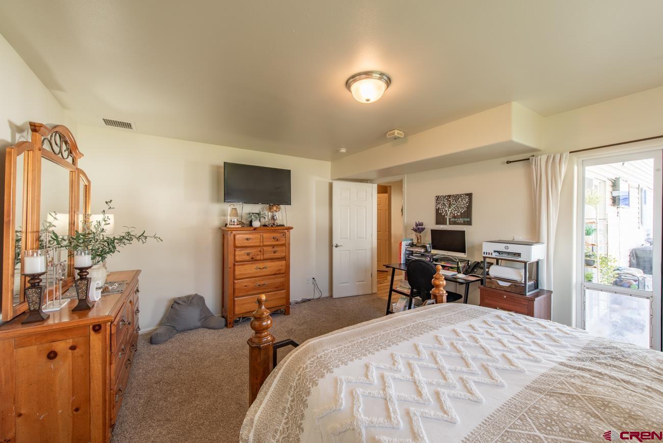 111 6675th Road Montrose, CO 81401 - Photo 18 of 40 a bedroom with a bed and a flat tv screen tv on the dresser