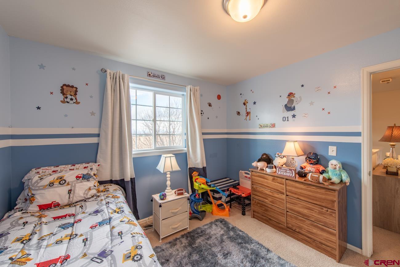 111 6675th Road Montrose, CO 81401 - Photo 27 of 40 a bed room with bed and two windows