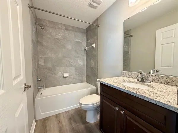 a bathroom with a granite countertop sink toilet a shower and a mirror