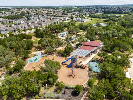 an aerial view of residential houses with outdoor space and trees