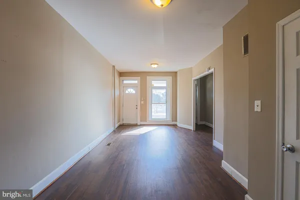 a view of an empty room with wooden floor and windows