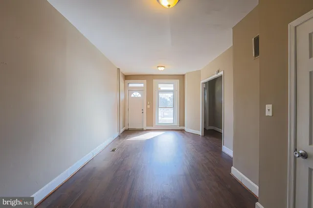 a view of an empty room with wooden floor and windows