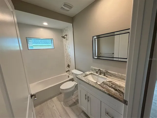 a bathroom with a granite countertop sink mirror vanity and toilet