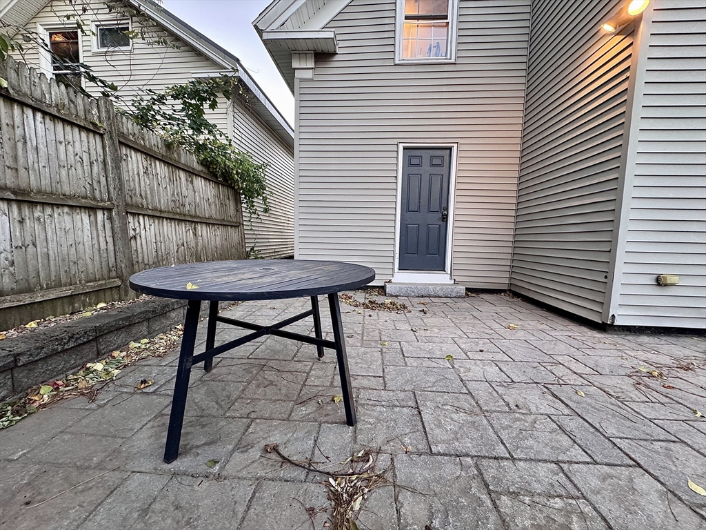7 Hardy Street, Unit 1 Beverly, MA 01915 - Photo 17 of 24 a view of a backyard with a table and chairs and wooden fence
