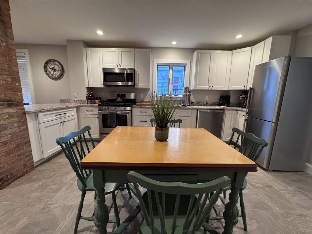7 Hardy Street, Unit 1 Beverly, MA 01915 - Photo 5 of 24 a kitchen with a dining table and chairs