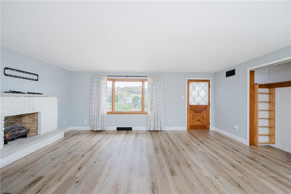 89 Marcoline Road Home, PA 15747 - Photo 12 of 47 an empty room with windows a fireplace and wooden floor