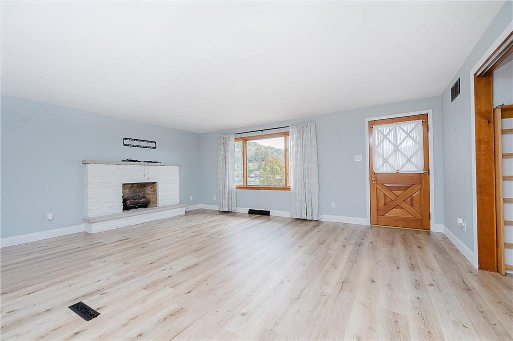89 Marcoline Road Home, PA 15747 - Photo 13 of 47 an empty room with wooden floor fireplace and windows