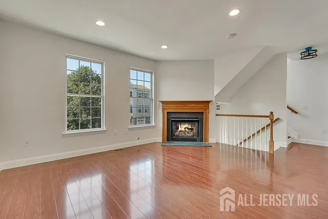 a view of an empty room with wooden floor fireplace and a window