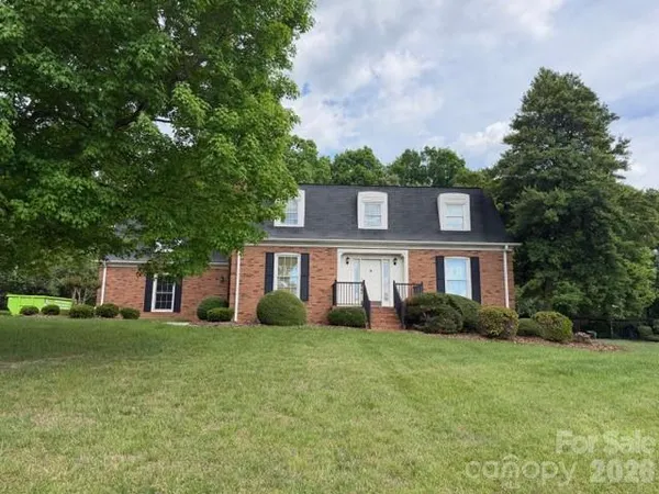 a view of a house with a big yard and large trees