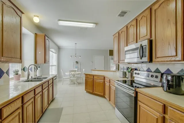 a kitchen with stainless steel appliances a sink dishwasher stove refrigerator and cabinets