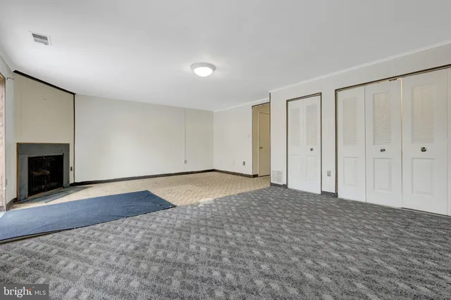 an empty room with wooden floor fireplace and windows