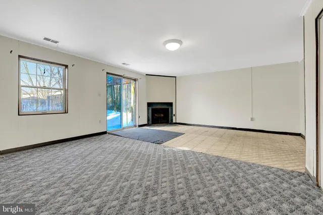 an empty room with windows and fireplace