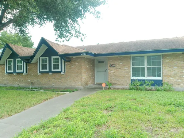 a view of a house with a yard and a large tree