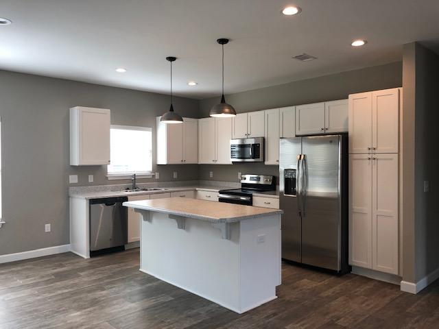 343 Indian Woman Road Santa Rosa Beach, FL 32459 - Photo 2 of 21 a kitchen with kitchen island granite countertop a refrigerator a sink dishwasher a stove and white cabinets with wooden floor