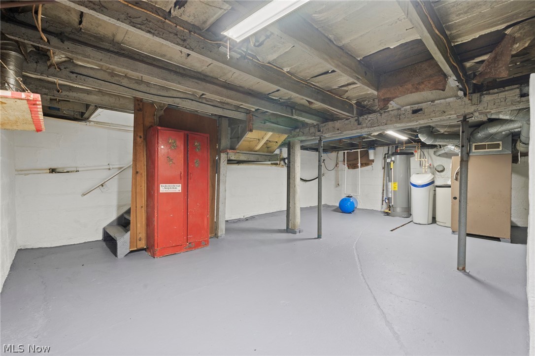1218 Briggle Road Akron, OH 44320 - Photo 25 of 40 Basement space featuring exposed ceiling joists, painted concrete flooring, and a water heater