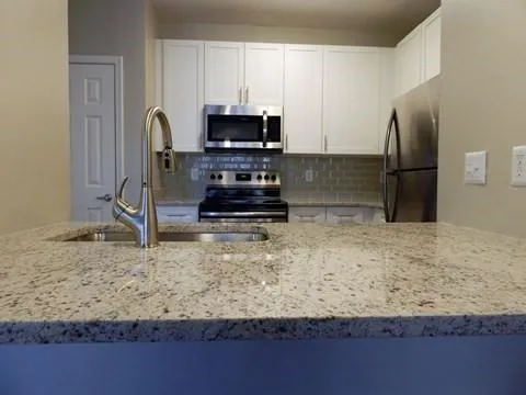 a kitchen with kitchen island granite countertop a sink stove and refrigerator