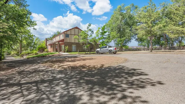 a view of a house with a yard and large trees