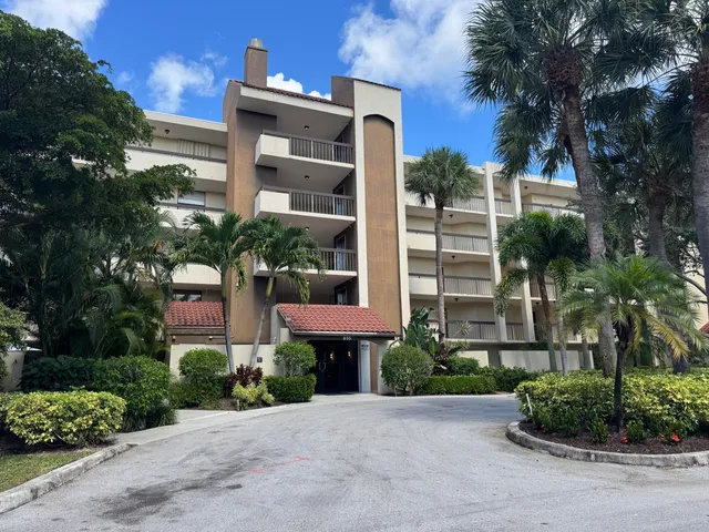 a front view of a multi story residential apartment building with yard and green space
