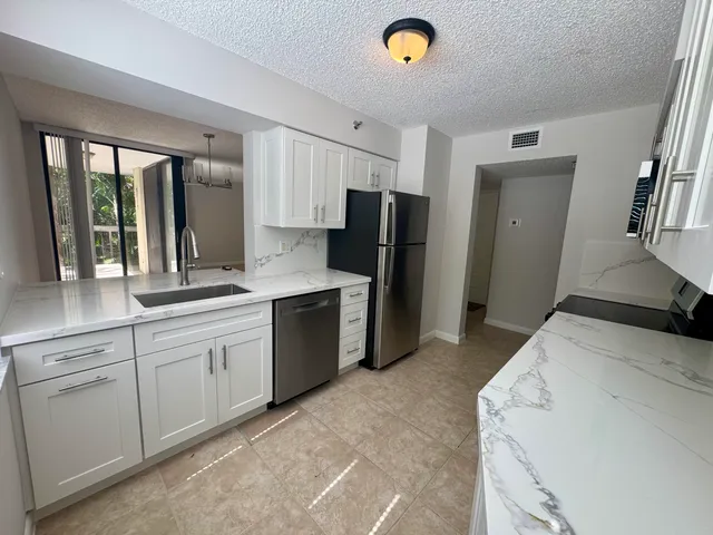 a kitchen with stainless steel appliances granite countertop a refrigerator and a sink