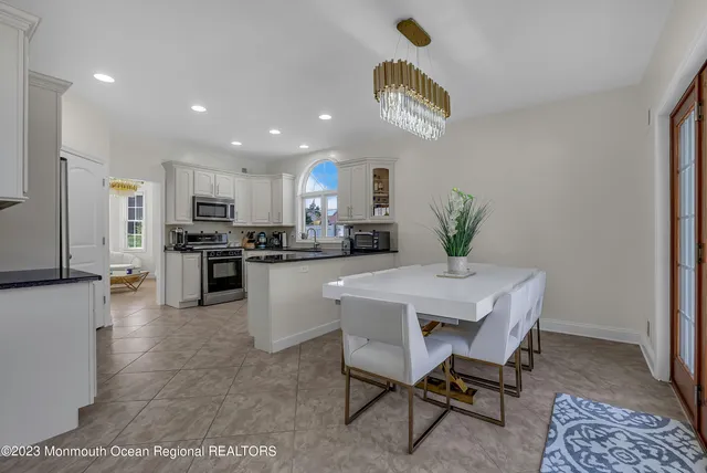 a kitchen with stainless steel appliances granite countertop a stove top oven a sink a dining table and chairs