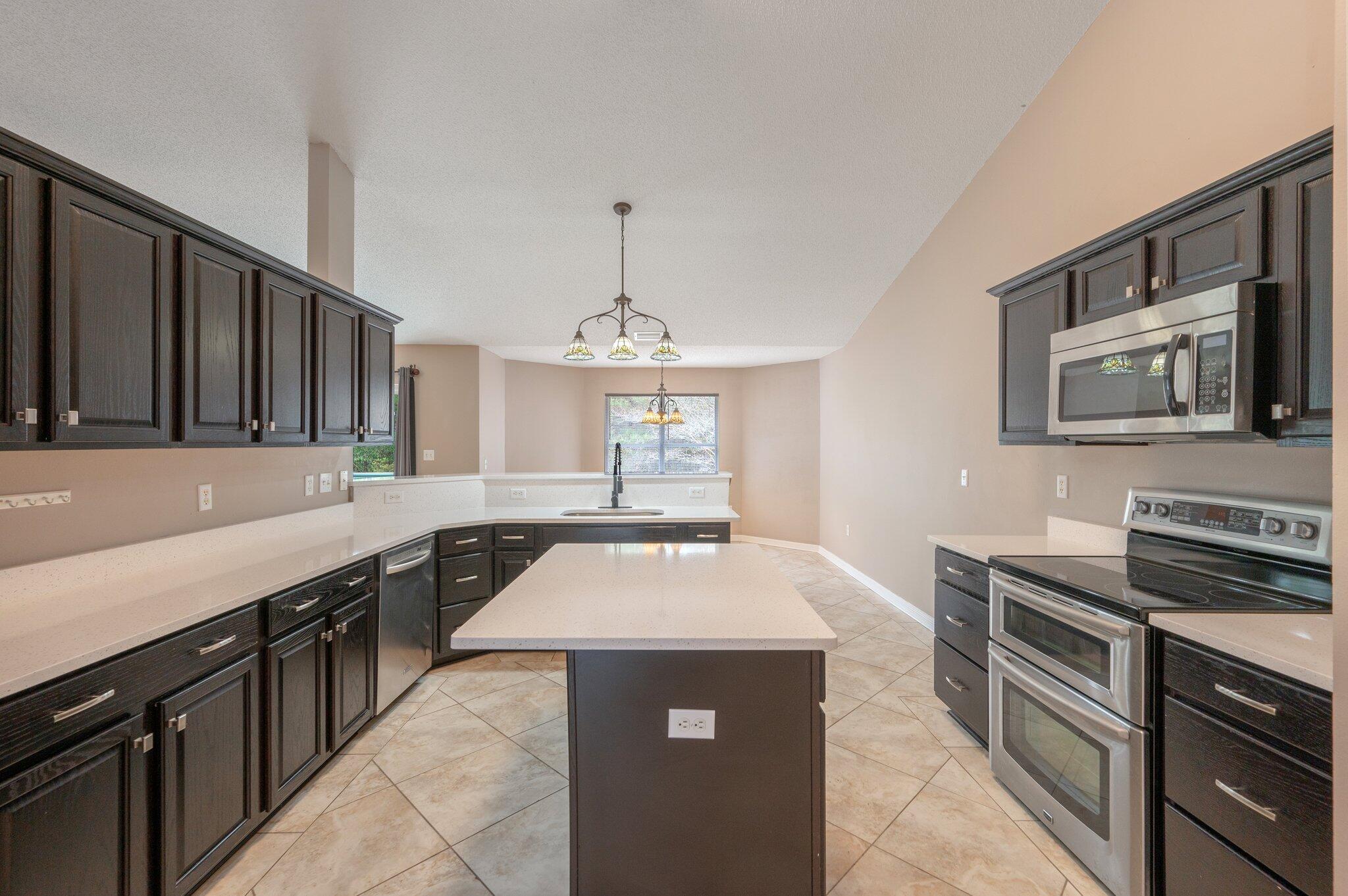 4752 Balboa Road Crestview, FL 32539 - Photo 13 of 46 a kitchen with stainless steel appliances granite countertop a stove a sink dishwasher and a microwave oven with white cabinets