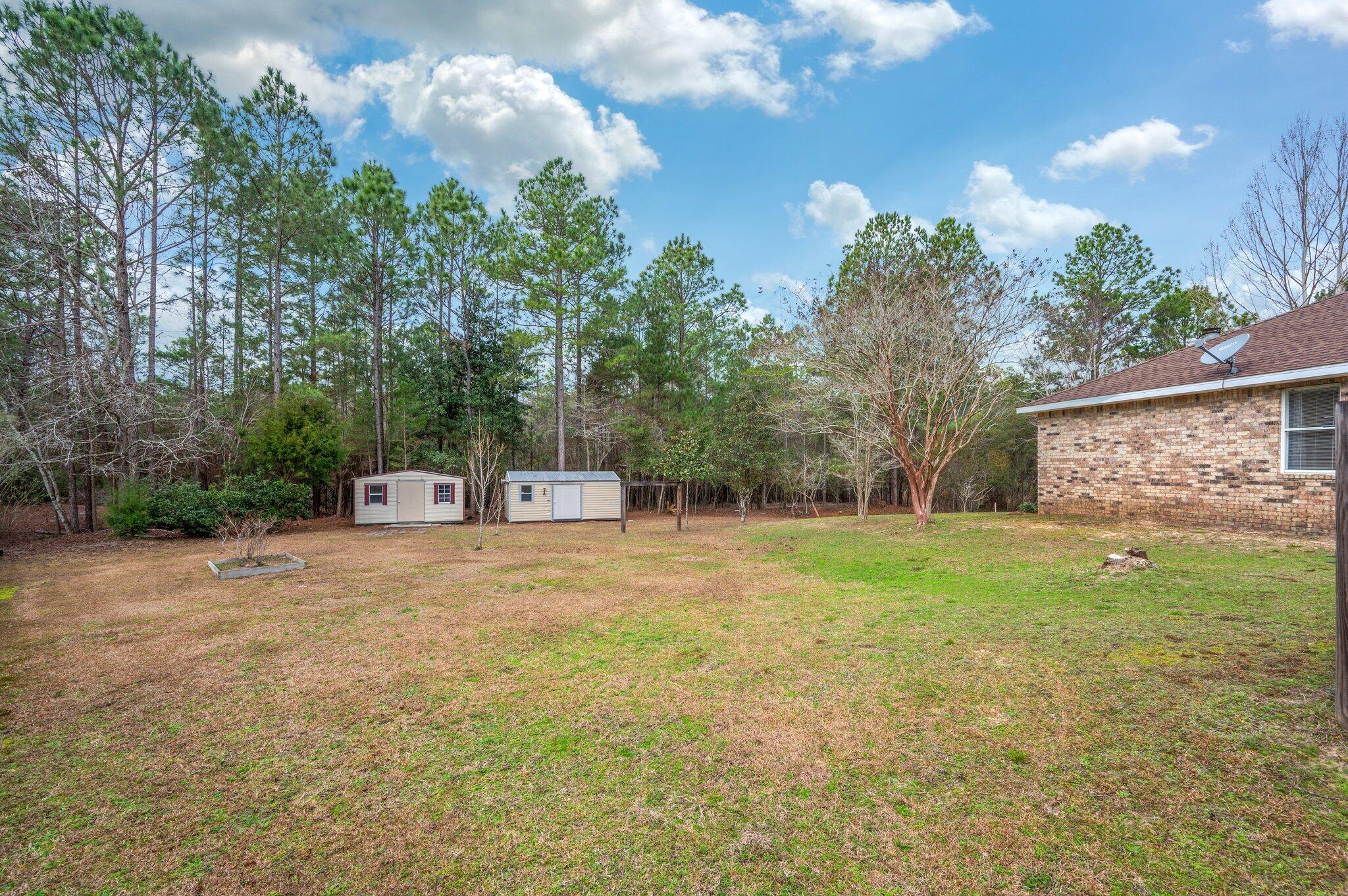 4752 Balboa Road Crestview, FL 32539 - Photo 41 of 46 a backyard of a house with plants and large trees