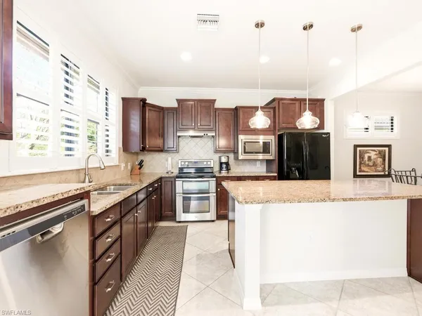 a large kitchen with stainless steel appliances granite countertop a stove a sink and a refrigerator