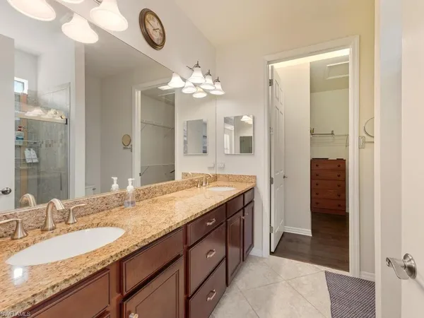 a spacious bathroom with a granite countertop double vanity sink a mirror and a shower