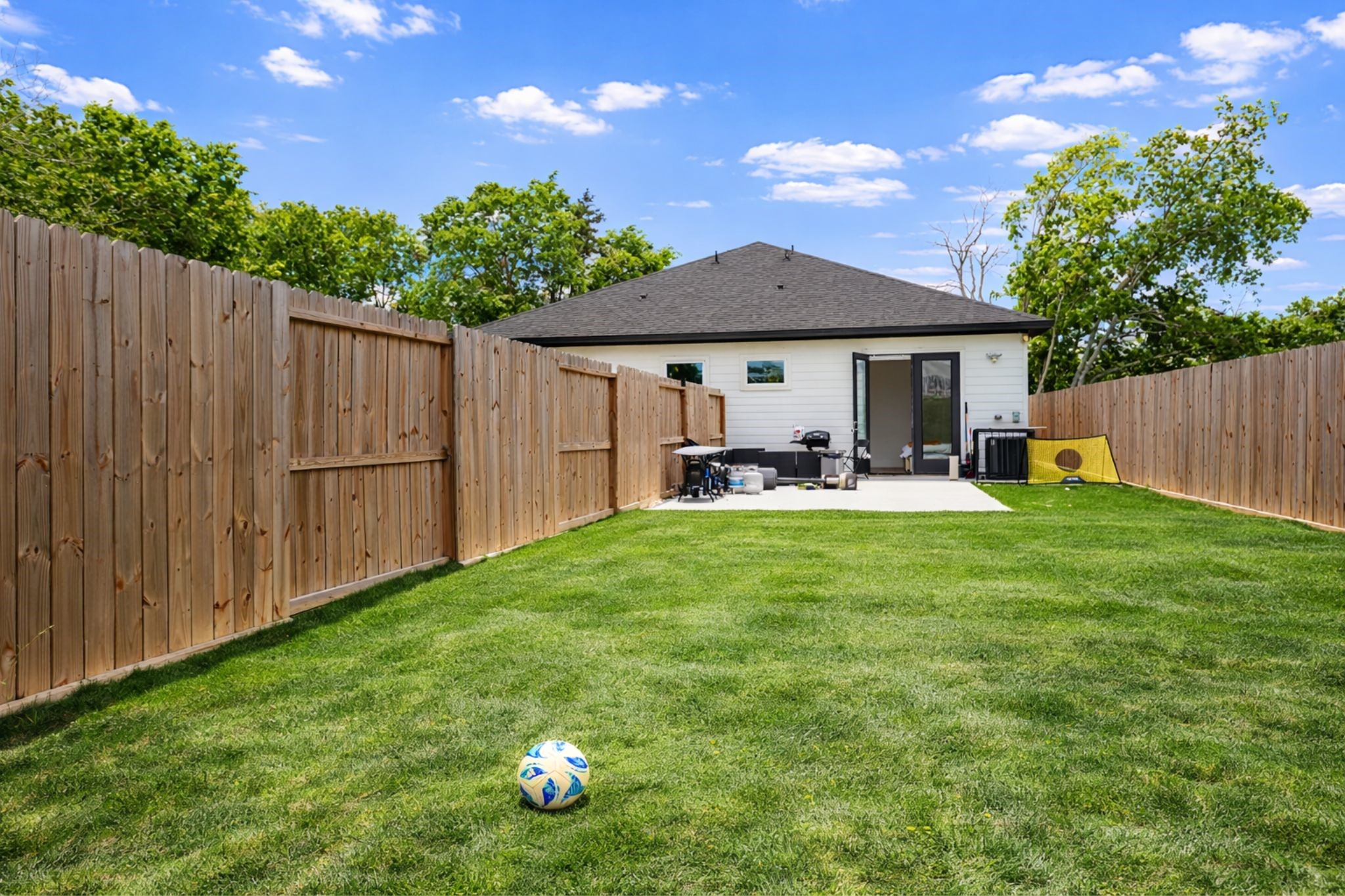 3549 Amos Street Houston, TX 77021 - Photo 16 of 25 Oversized, fully fenced backyard offering plenty of room for outdoor living, entertaining, or pets. Enjoy a private setting with a clean patio area perfect for grilling or relaxing, plus a wide open lawn ideal for play or future customization. A great extension of the home with endless possibilities for everyday enjoyment. The grass is AI enhanced.